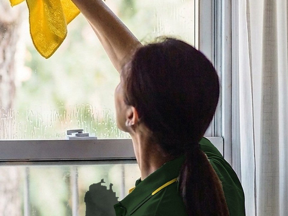 BrightHome cleaner wiping window glass for a Houston move-out clean